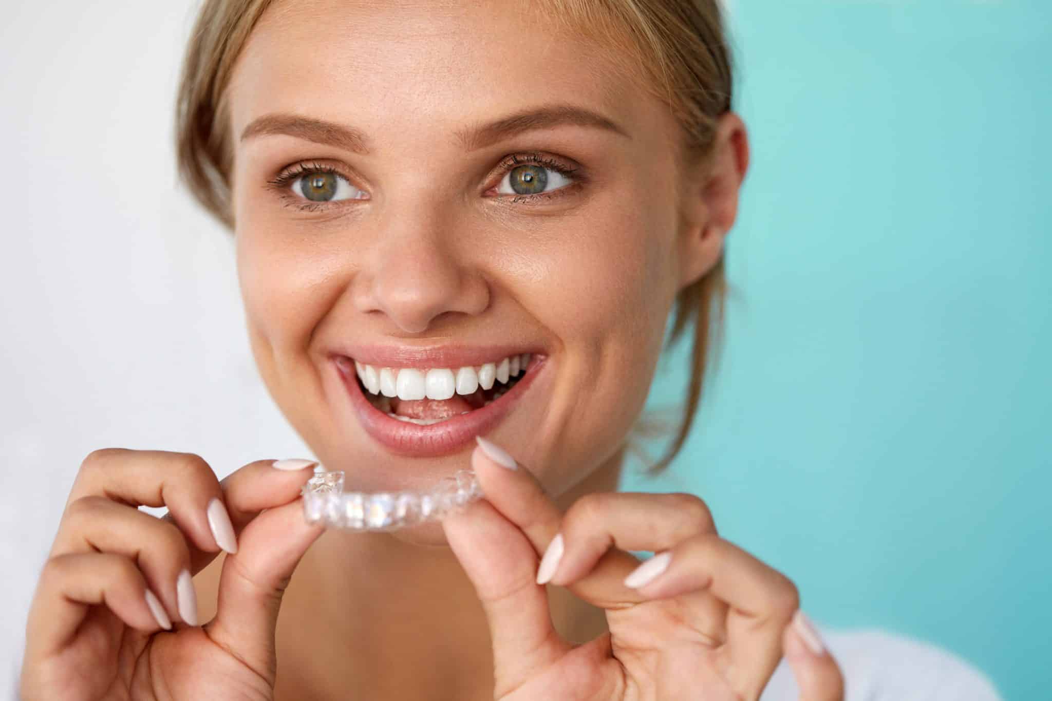 Stock photo of a smiling woman holding a clear dental tray