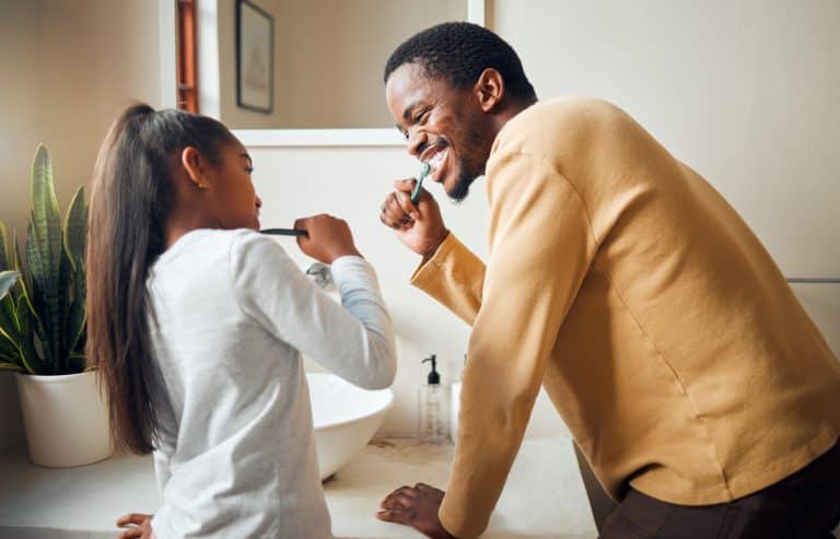 Oral care, brushing teeth and father with daughter in bathroom for hygiene, grooming and bonding.