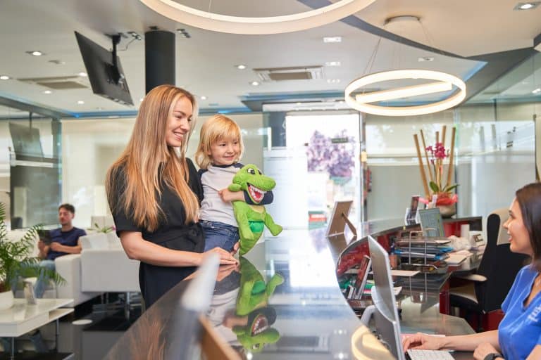 mother holds her child in her arms at the dentist's reception desk Veranda Family Dentistry
